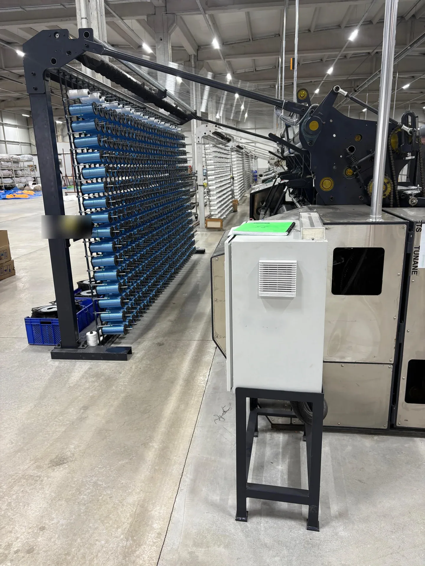 Creel of blue polyamide monofilament bobbins next to a net-making loom at the Tunanets plant